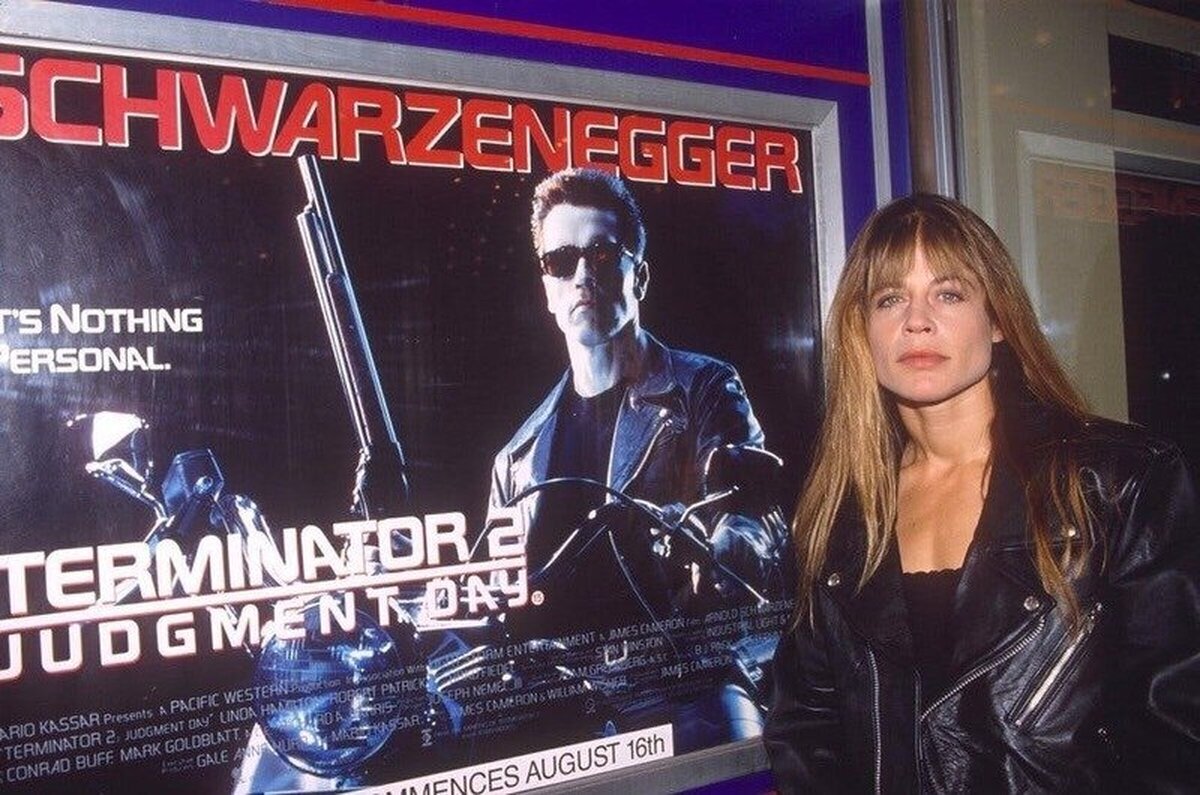 Linda Hamilton junto al poster de la pelicula "terminator 2" (1991)  