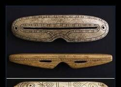 Enlace a Antes de que existieran las gafas de sol, los pueblos indígenas del Ártico tallaban estos protectores en hueso, madera y marfil para prevenir la ceguera por la nieve. Las estrechas ranuras crean un efecto similar al de un agujero estenopeico