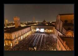 Enlace a Proyección al aire libre de la película *The Matrix* durante el verano en la plaza medieval Piazza Maggiore, Bolonia, Italia.