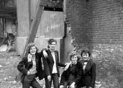 Enlace a Jóvenes de clase trabajadora en Londres, pertenecientes a la nueva y rebelde subcultura juvenil Teddy Boy/Girl, posan en un terreno devastado por bombardeos en 1955, exhibiendo su estilo inspirado en la época eduardiana. Fotografía tomada por Ken Russell.