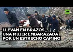 Enlace a Cargan con una mujer embarazada por un camino estrecho y montañoso para llegar al hospital