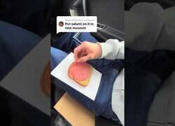Enlace a Enmarcando una rebanada de pan con salami y colgándola en la pared de un museo
