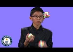 Enlace a El niño que resuelve 3 cubos de Rubik mientras hace malabares con ellos